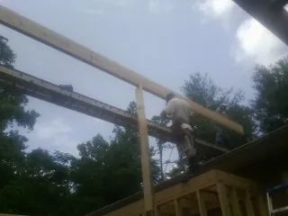 Carpenter setting a ridge beam over a new addition frame — Ice Dam Removal by Roofing Brothers in Wanette