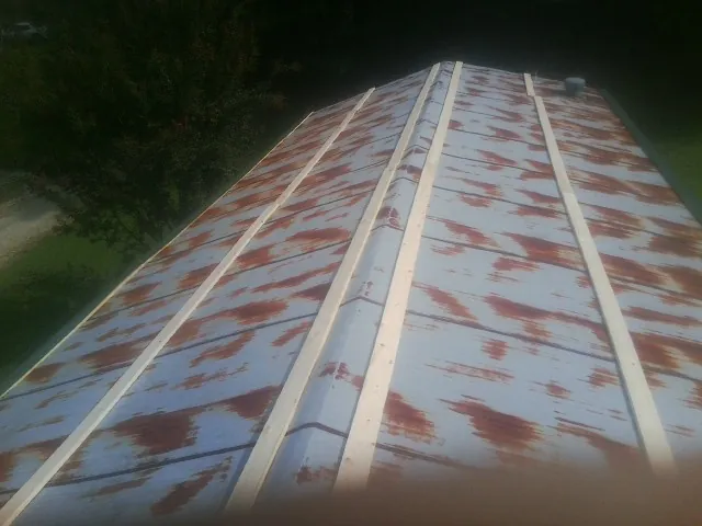 Rusted metal roof panels with new wood purlins before replacement — Storm Damage Roof Repair in Wanette by Roofing Brothers