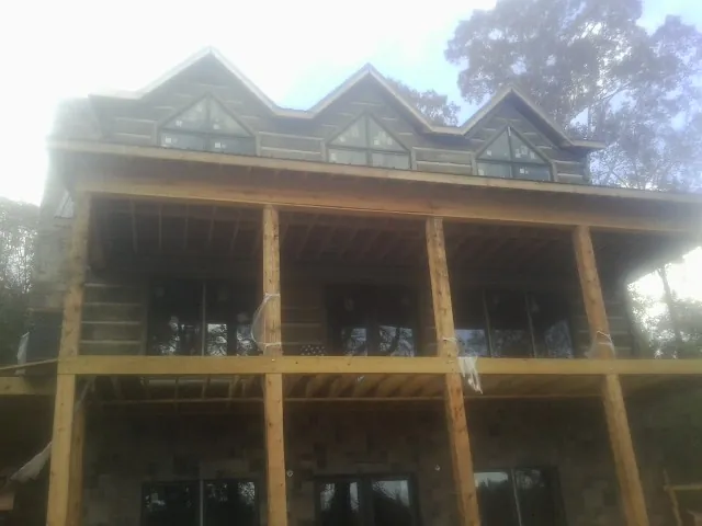 Dormers and porch framing on a large log home under construction — Roof Coating work by our crew in Wanette