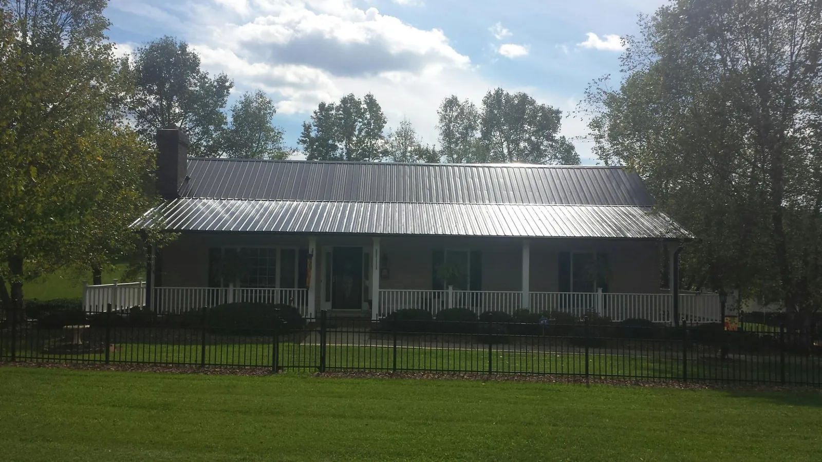 Gray metal roof on a brick ranch with a full width front porch — Gutter Guard Installation work by our crew in Wanette