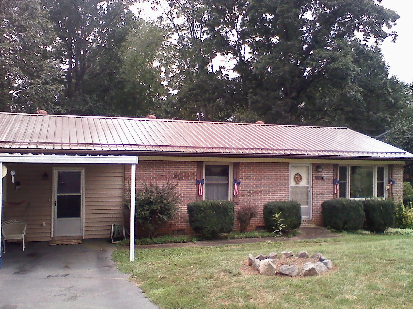 Bronze metal roof and carport on a brick ranch home — Roof Repair work by our crew in Wanette
