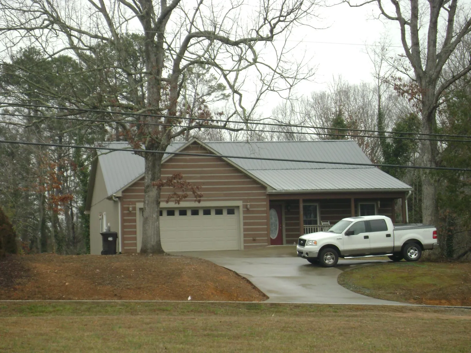 Gray metal roof on a log sided house with an attached two car garage in Wanette