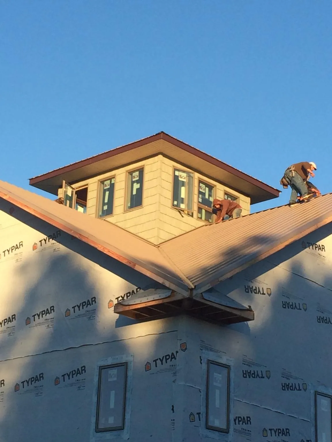 Roofers working around a rooftop cupola on a new metal roof at sunset — Roof Waterproofing in Wanette by Roofing Brothers